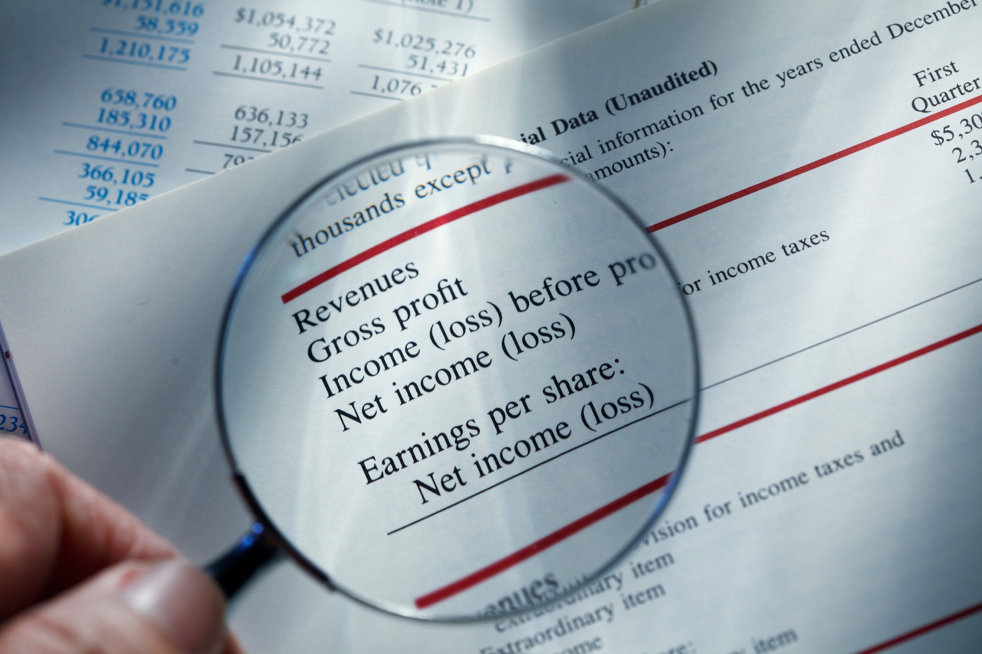 Man Holding Magnifying Glass Over Financial Report